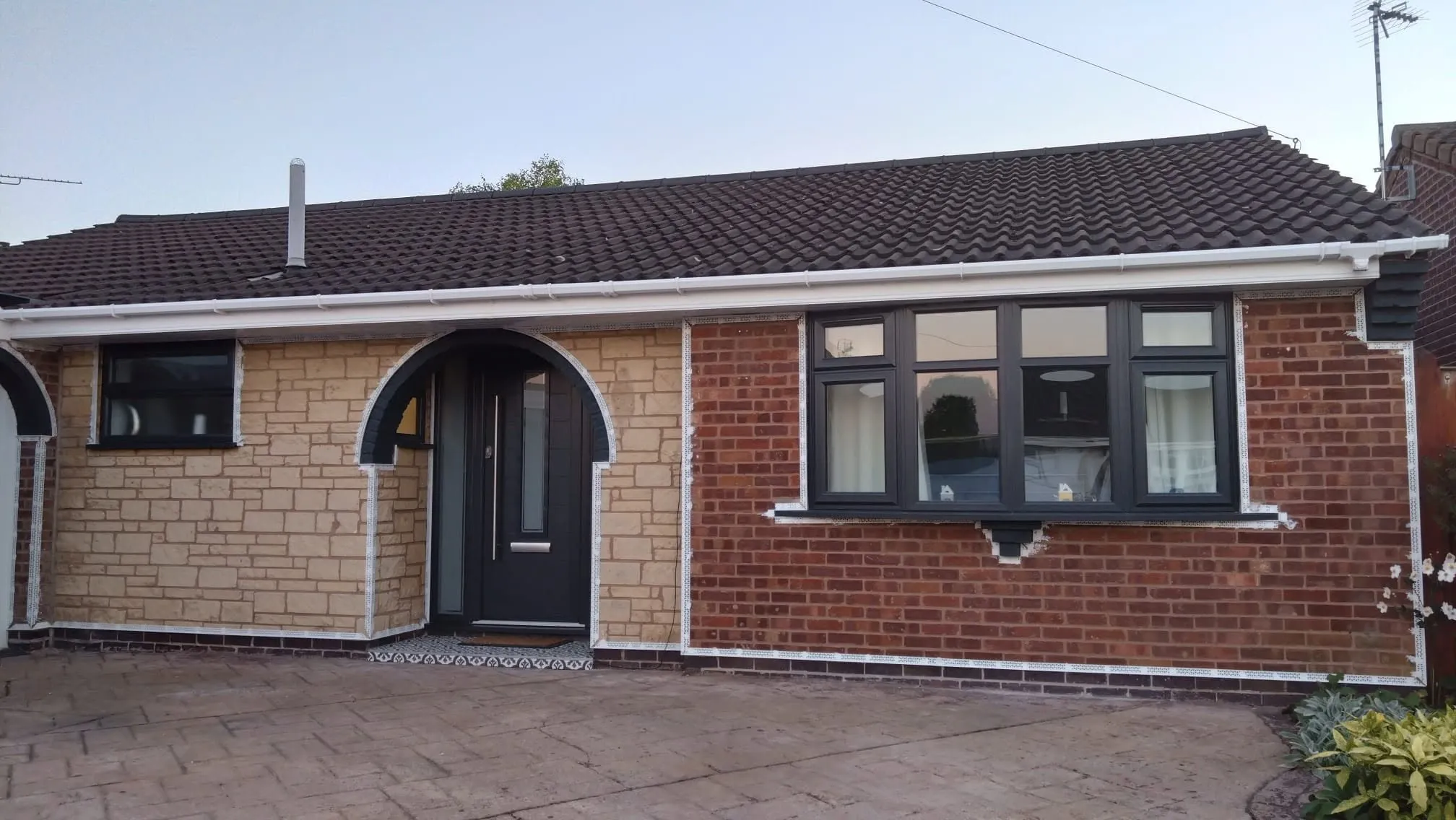 A bungalow before rendering: mismatched reconstituted stone and red brickwork with beading visible around the windows.