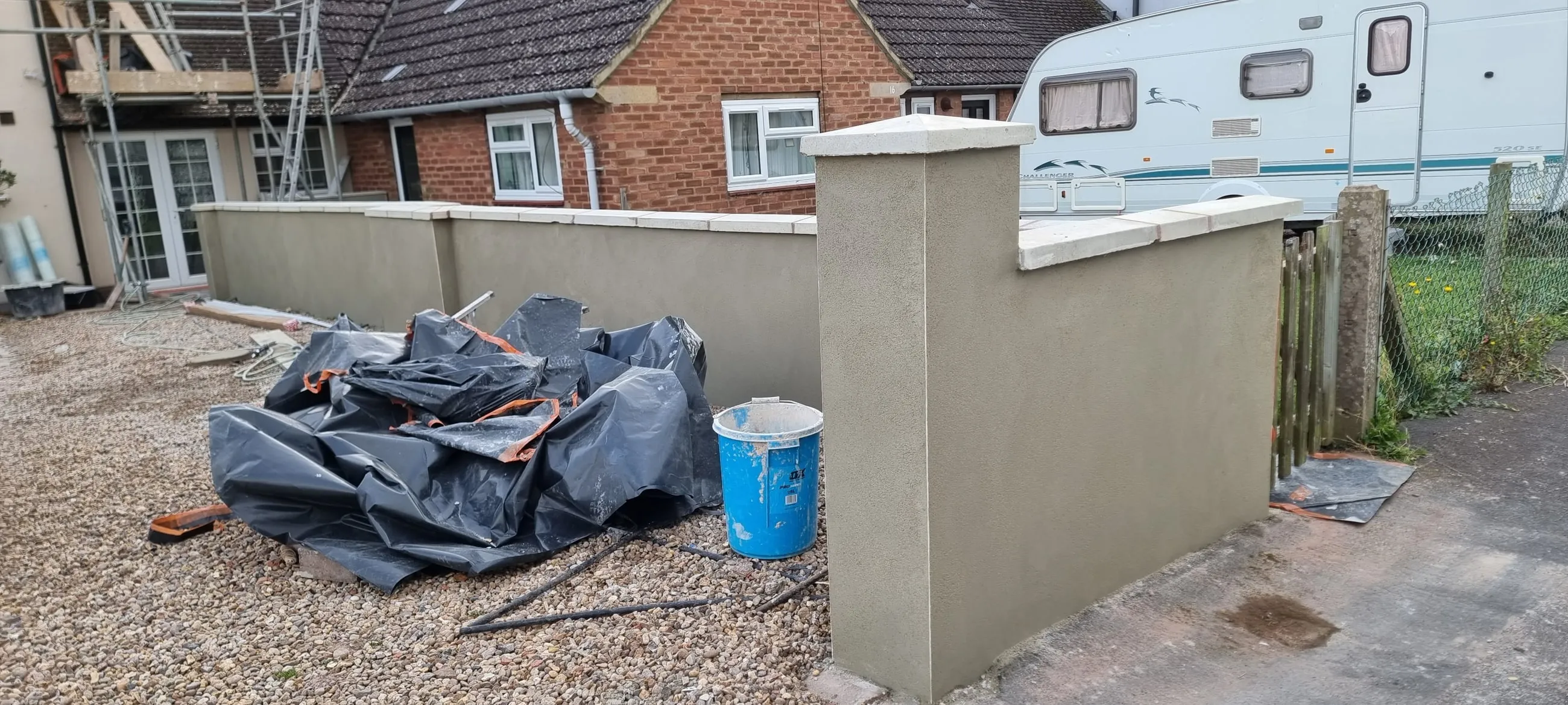 A rendered garden wall and pillar finished in smooth cream render, with the house behind.